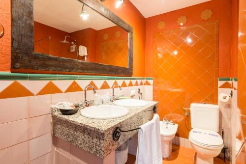 Un baño con lavabo, inodoro y espejo. en Hostal El Escudo de Mijas, en Mijas