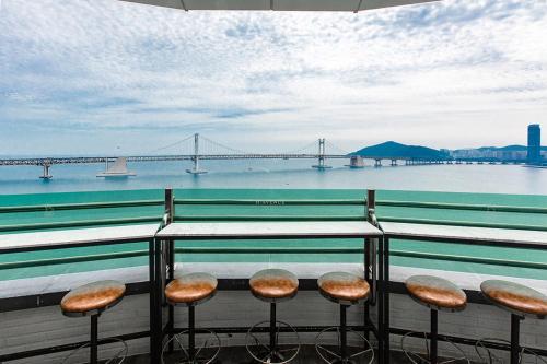 a group of stools on a balcony with a view of a bridge at H Avenue Hotel Gwangalli branch in Busan