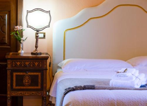 a bedroom with a bed with a lamp and a dresser at Palazzo Sismonda in Corneliano d'Alba