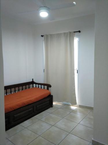a bedroom with a bed with an orange blanket and a window at Echague y Cura A Montiel in Paraná