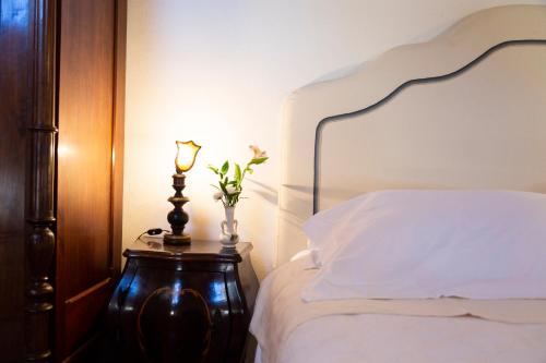 a bed with a nightstand with a vase of flowers on it at Palazzo Sismonda in Corneliano d'Alba