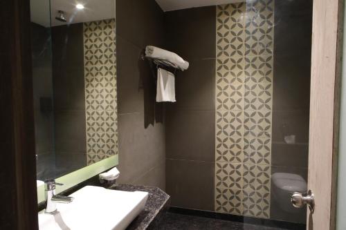 ein Bad mit einem Waschbecken, einem WC und einer Dusche in der Unterkunft Kingston Resort in Kānpur