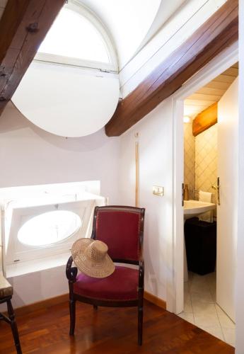 a red chair with a hat on a table in a bathroom at Palazzo Sismonda in Corneliano d'Alba