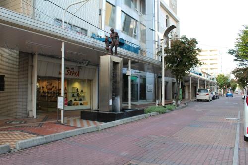 a man sitting on the side of a building on a street at NY Building 4th Floor, Guest House Ichibangai, Roo / Vacation STAY 55912 in Kitami