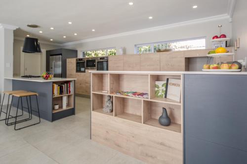 a kitchen with wooden cabinets and a counter with a table at The Little Palm in Bloubergstrand