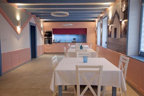 a dining room with tables and a kitchen in the background at Lehel Vendégház in Szekszárd