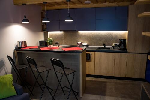 een keuken met blauwe kasten en een bar met krukken bij My Studio - La Magazie in Braşov