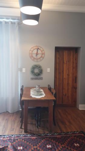 a dining room table with a clock on the wall at The Fancy Cactus in Colesberg