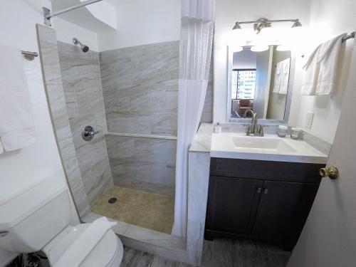 a bathroom with a shower and a sink and a toilet at Waikiki Monarch Hotel in Honolulu