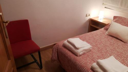ein Schlafzimmer mit einem roten Stuhl und einem Bett mit zwei Handtüchern in der Unterkunft Céntrico y luminoso San Vicente in Salamanca