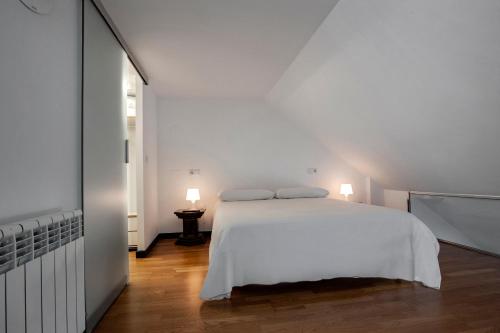 - une chambre blanche avec un lit blanc et deux lampes dans l'établissement Oktheway Loft Maestranza, à La Corogne