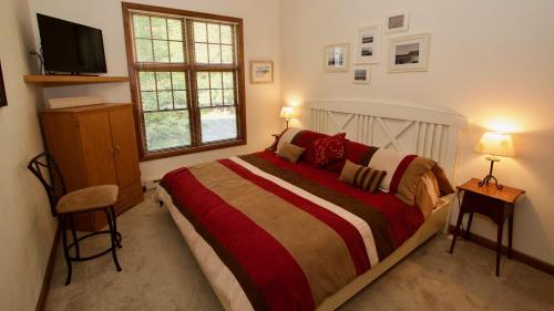 a bedroom with a bed and two chairs and a television at Baileys Harbor Yacht Club Resort in Baileys Harbor