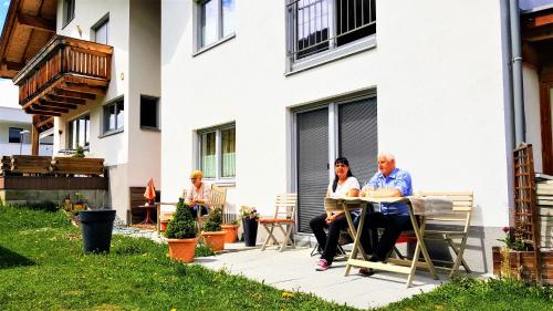 three people sitting at a table outside of a house at Ferienhaus Gundi in Pettneu am Arlberg