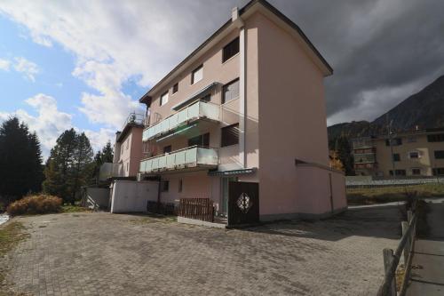 ein rosafarbenes Apartmenthaus auf einer unbefestigten Straße in der Unterkunft Golf Apartments - Schmid in Davos