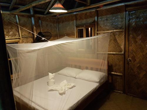 uma pequena cama num quarto com uma rede em Backpacker's Hill Resort em San Vicente