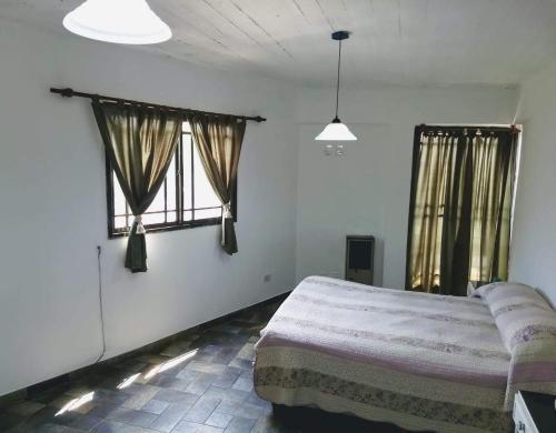 um quarto com uma cama e duas janelas em Alojamiento Entero con Excelente Ubicación em Morón