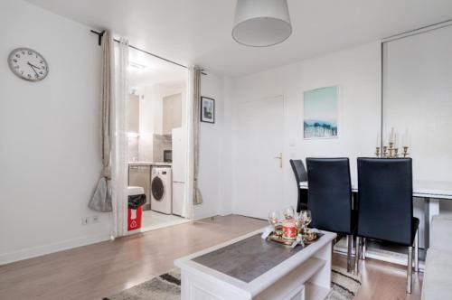 uma sala de estar branca com uma mesa e cadeiras em Appartement spacieux avec terrasse près de Paris et du Stade de France em Saint-Denis