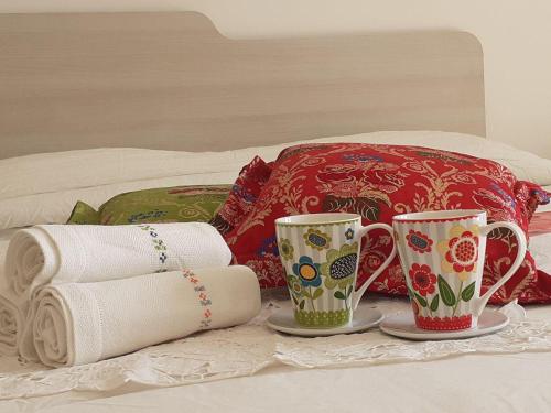 2 tazas en una cama con toallas y almohadas en B&B Pascal, en Cagliari