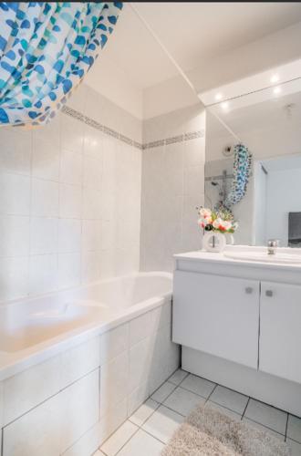 une salle de bain blanche avec une baignoire et un lavabo dans l'établissement Appartement spacieux avec terrasse près de Paris et du Stade de France, à Saint-Denis