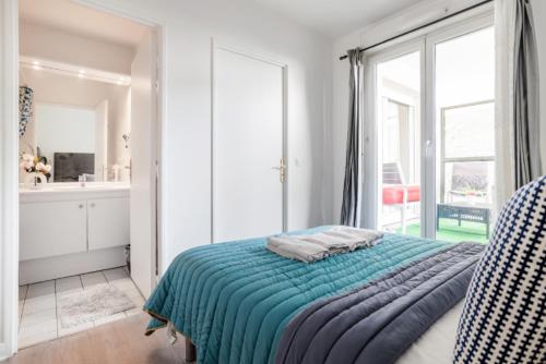 um quarto com uma cama e uma grande janela em Appartement spacieux avec terrasse près de Paris et du Stade de France em Saint-Denis