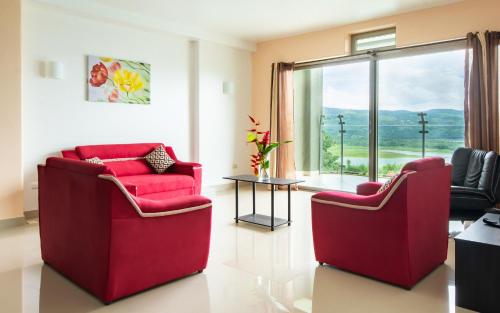 two red chairs in a living room with a window at Lake Arenal Condos in Naranjos Agrios