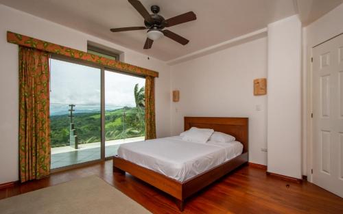 a bedroom with a bed and a large window at Lake Arenal Condos in Naranjos Agrios
