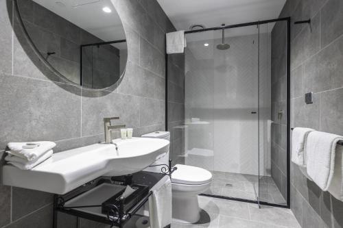 a bathroom with a sink and a toilet and a mirror at Q Squared Serviced Apartments in Melbourne