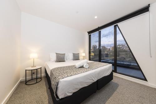 a bedroom with a bed and a large window at Q Squared Serviced Apartments in Melbourne