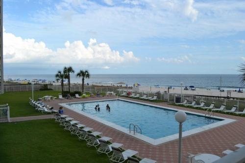 a large swimming pool with chairs and the beach at Sunswept 703 Condo in Orange Beach
