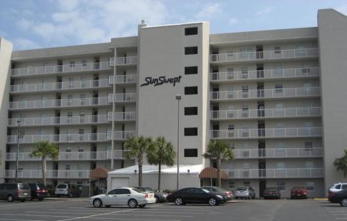 a large apartment building with cars parked in a parking lot at Sunswept 703 Condo in Orange Beach