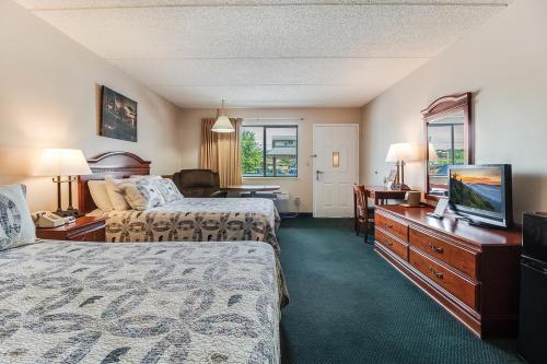 a hotel room with two beds and a flat screen tv at Mountain Breeze Motel in Pigeon Forge