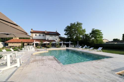 une piscine avec des chaises blanches et une maison dans l'établissement B&B La Corte Dei Vizi, à Clauiano