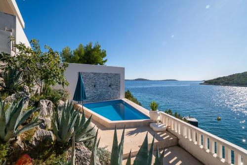 a house with a swimming pool next to the water at Villa Sine in Sevid