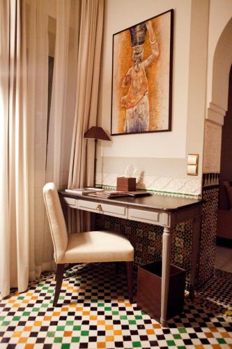 a desk with a chair and a painting on the wall at Palais Faraj Suites & Spa in Fès