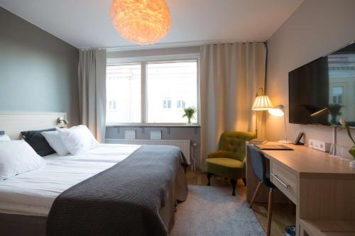 a hotel room with a bed and a desk and a window at Hotell Aston in Karlskrona
