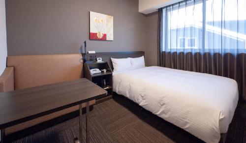 une chambre d'hôtel avec un lit et une fenêtre dans l'établissement Hotel Route-Inn Miyako, à Miyako