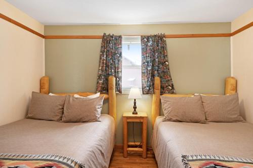 two twin beds in a room with a window at Foothills Lodge and Cabins in South Fork