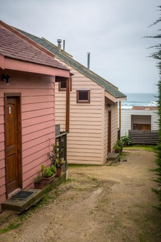 a pink building with a door and some plants at Cabañas Piedra Grande in Pichilemu