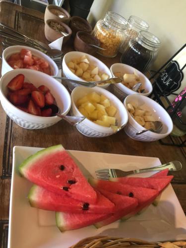 a table with a plate of watermelon and bowls of fruit at Finca el Maitén Hotel Boutique in San Rafael