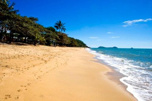 a beach with footprints in the sand next to the ocean at The Beach Shack 3BR Waterfront Resort, Own WIFI in Trinity Beach