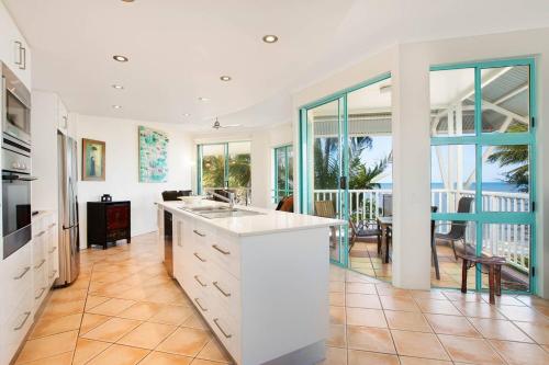 a kitchen with white cabinets and a view of the ocean at The Beach Shack 3BR Waterfront Resort, Own WIFI in Trinity Beach