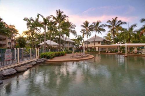 a pool of water at a resort with palm trees at The Beach Shack 3BR Waterfront Resort, Own WIFI in Trinity Beach