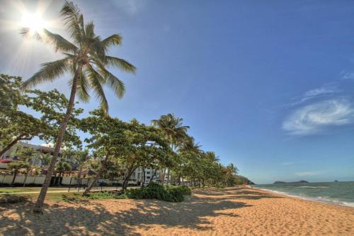 a beach with palm trees and the ocean at The Beach Shack 3BR Waterfront Resort, Own WIFI in Trinity Beach
