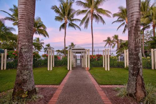 a white entrance to a park with palm trees at The Beach Shack 3BR Waterfront Resort, Own WIFI in Trinity Beach