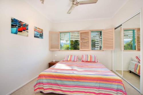 a bedroom with a bed with a colorful striped blanket at The Beach Shack 3BR Waterfront Resort, Own WIFI in Trinity Beach