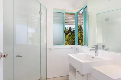 a bathroom with a sink and a glass shower at The Beach Shack 3BR Waterfront Resort, Own WIFI in Trinity Beach