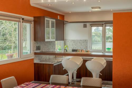 a kitchen with orange walls and a table and chairs at Complejo Villa Don Cata in Quequén