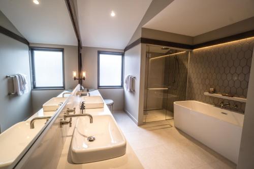 a bathroom with three sinks and a tub and a shower at Gibbston Valley Lodge and Spa in Queenstown