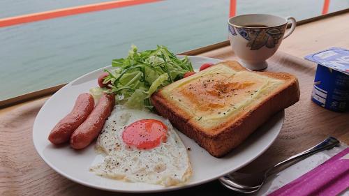 a plate of breakfast food with eggs toast and a cup of coffee at Sea Side Hostel Light House in Onomichi