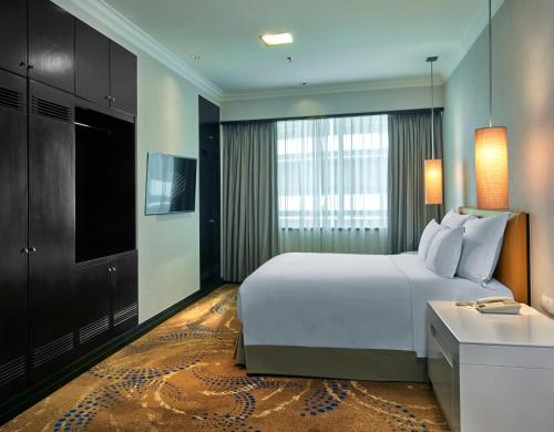 a hotel room with a large bed and a television at Pullman Kuala Lumpur City Centre Hotel & Residences in Kuala Lumpur
